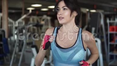 在健身房跑步机上跑步的女孩。 做有氧运动的年轻女人。 在健身房锻炼，跑步机